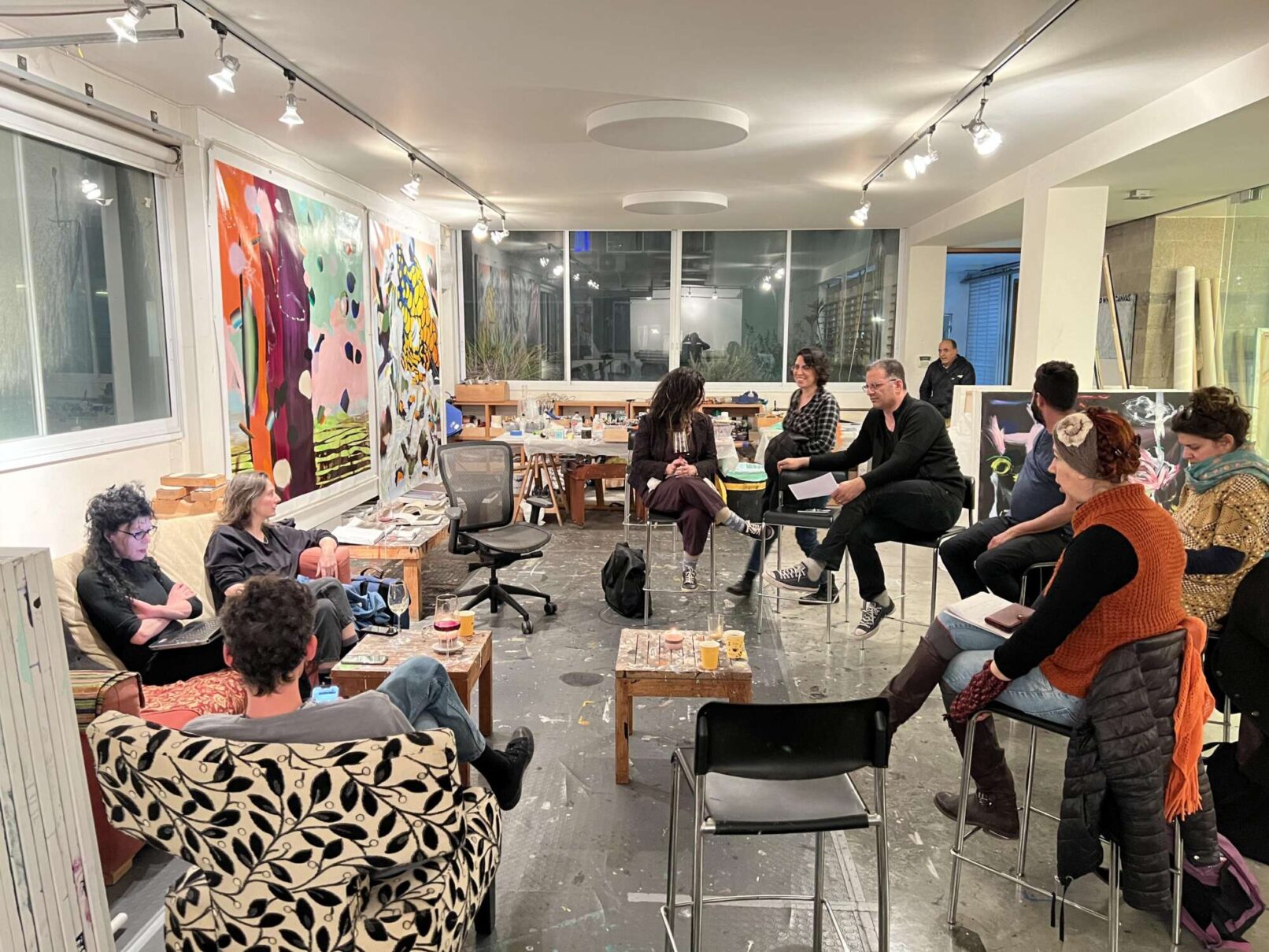 People sitting on an art studio. There are canvases with paintings